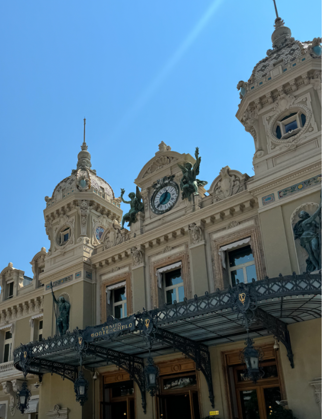 Monaco casino with a facade with clock and people in front on a clear day