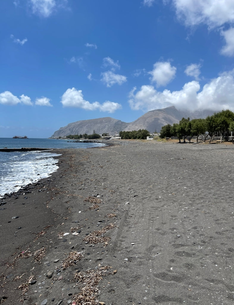 Walk along Santorini’s Black Sand Beach, where volcanic sand meets the sparkling Aegean Sea.
