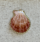 Shell pendant on a textured beige fabric background