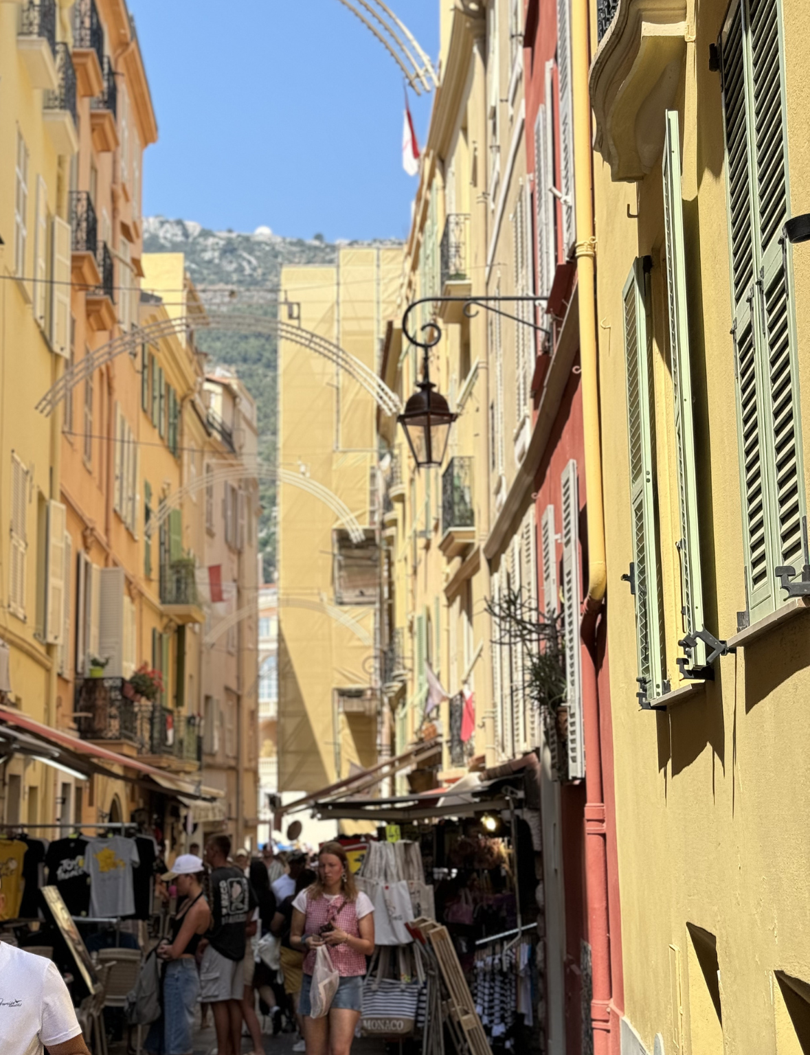  Monaco narrow street with colorful buildings and people in a sunny urban setting
