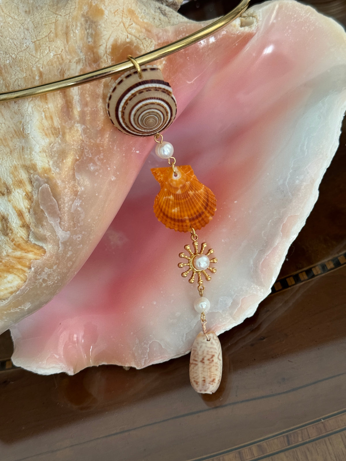 Love Ellison Pendant with shell and sun design on a large shell background